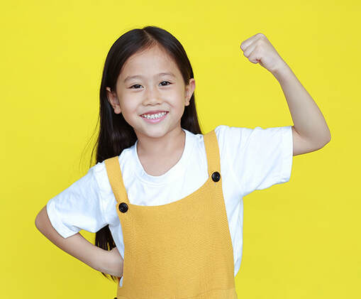 Young girl holding up one arm to show off her muscles.
